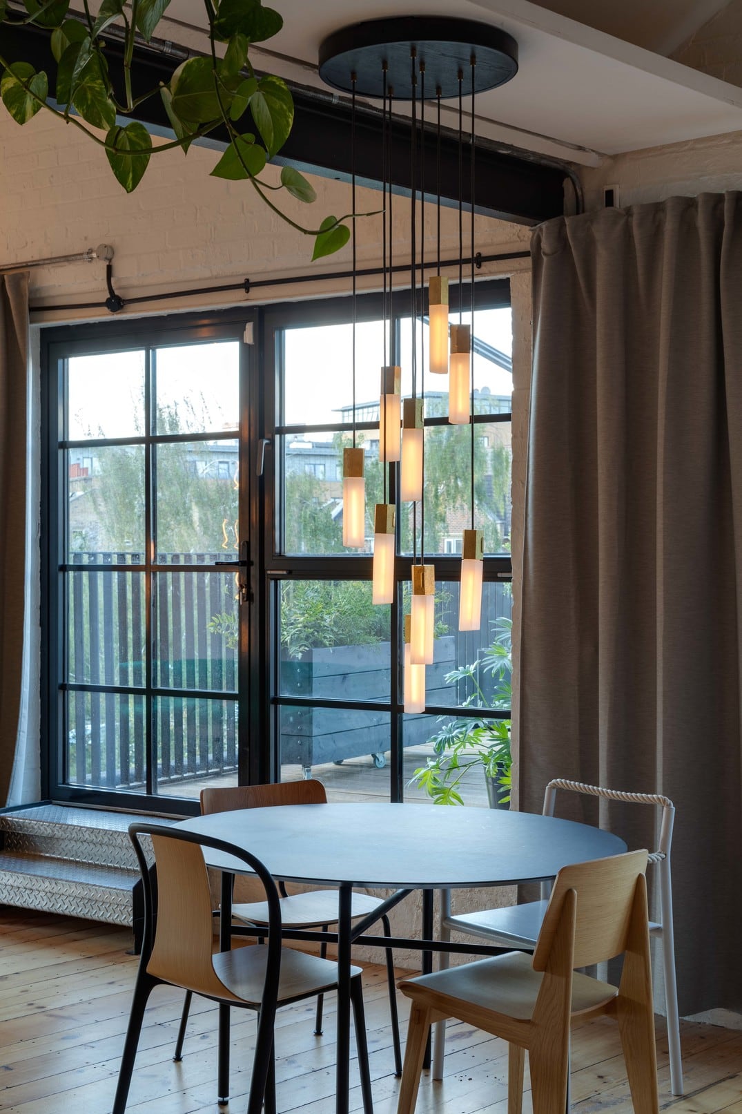 Tala Basalt Nine Pendant in brass hanging over a dining table. Free + fast UK delivery at someday designs. #colour_brass